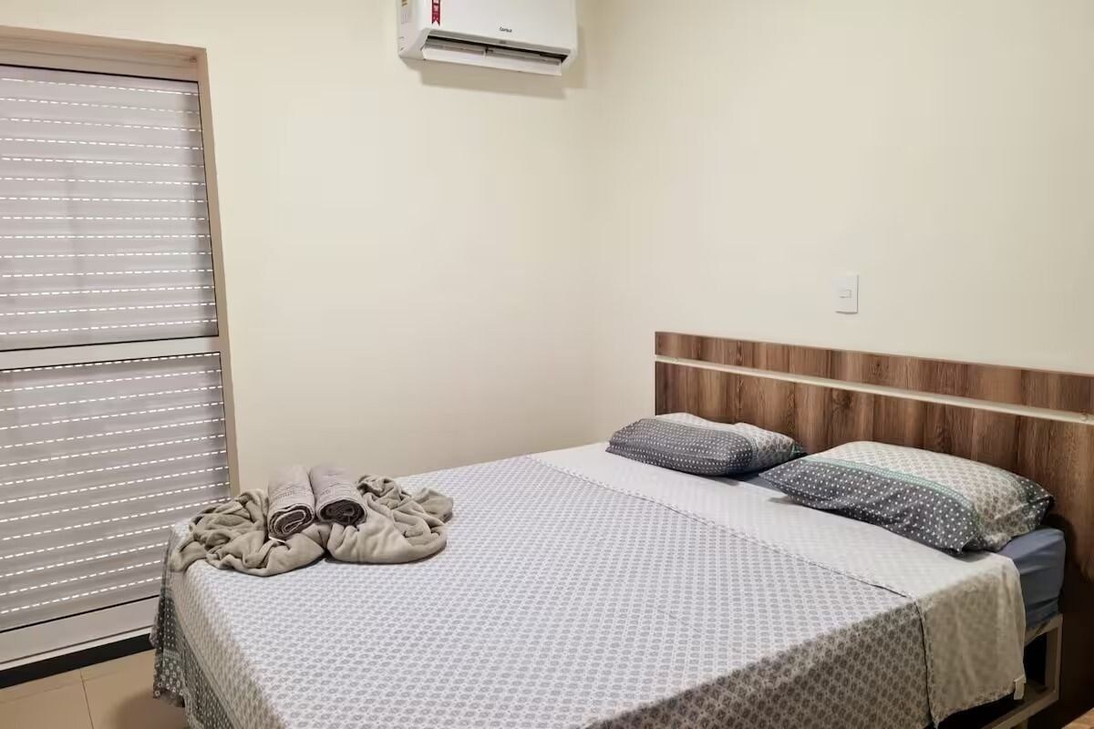 A single bed with a patterned bedspread, two pillows, and a folded blanket on the bed.