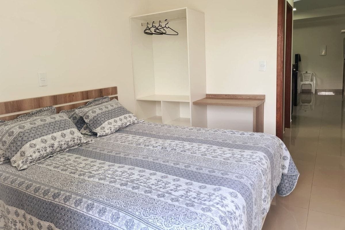 A bedroom with a bed, a wardrobe, and a small table.