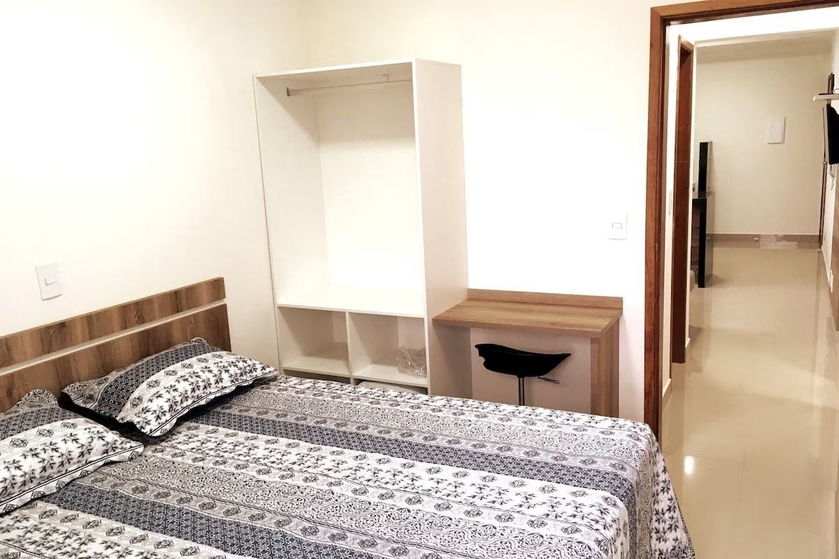 A bedroom with a bed, a bedside table, a wardrobe, and a mirror.