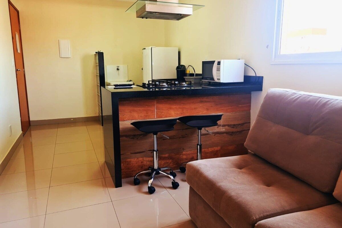 A compact living space with a kitchenette, a sofa, and a small bar area.