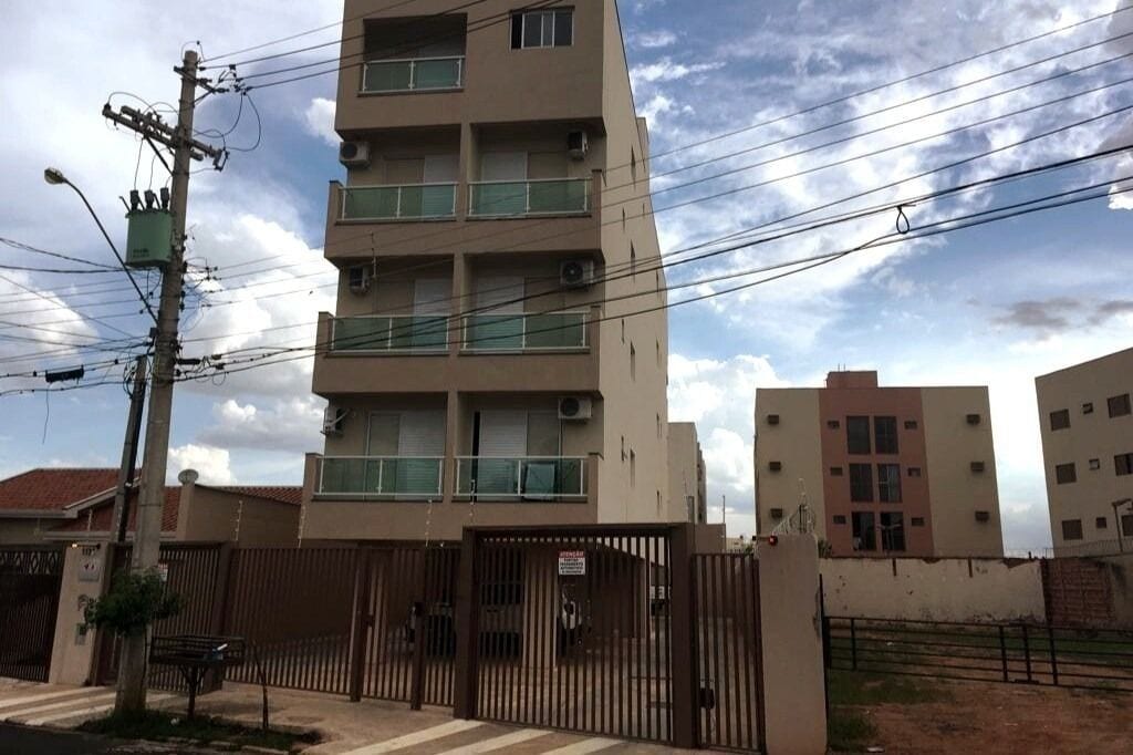 A multi-story building with a gated entrance, a utility pole with multiple wires, and a clear sky.