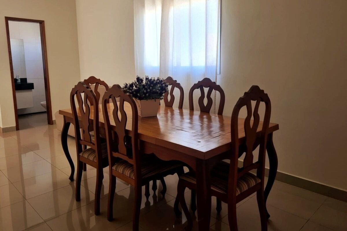 Un coin repas avec une table et des chaises en bois, une plante en pot et une fenêtre avec des rideaux.