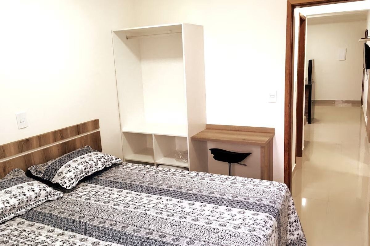 A bedroom with a bed, a wardrobe, a bedside table, and a mirror.