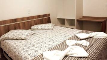 Cama bem arrumada com roupa de cama estampada e cabeceira de madeira.