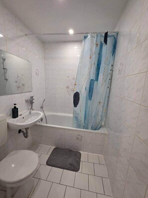 Ein Badezimmer mit Badewanne, Waschbecken, Toilette und Duschvorhang.