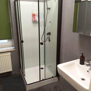 A bathroom with a glass-enclosed shower, a white sink, and a towel rack. - Leipzig Alt Lindenau Apartment – Sleeps 5, Parking (Leipzig)