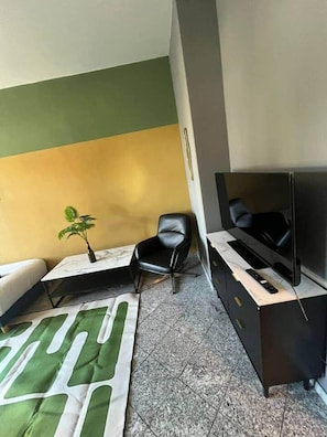 A modern living room with a sofa, a black chair, a TV on a stand, and a small plant. - Leipzig Alt Lindenau Apartment – Sleeps 5, Parking (Leipzig)