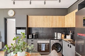 A modern kitchen with a microwave, oven, and washing machine. - KML Nine Palms Luxury 101 (Cape Town)