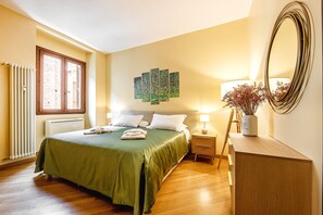 Ein Hotelzimmer mit Bett, Nachttisch, Spiegel, Heizkörper und Fenster.
