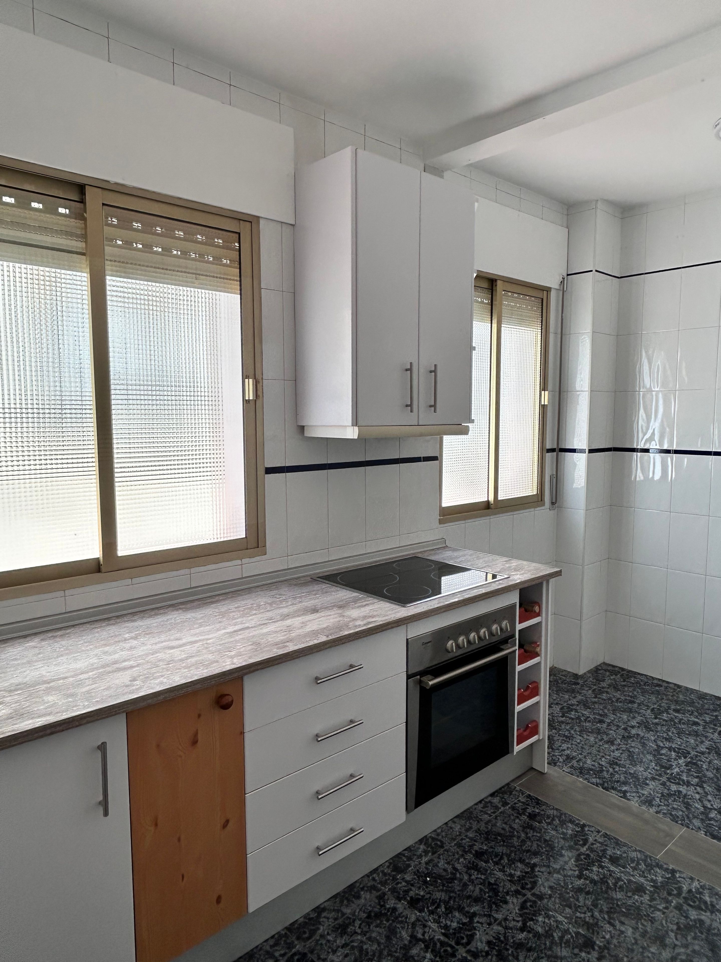 Una cocina con estufa, horno y ventana con persianas.