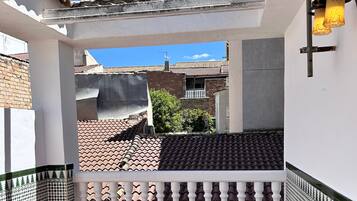 A balcony with a tiled floor, white balustrade, and a hanging light fixture.