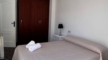 Una habitación de hotel con cama, mesita de noche, lámpara, armario y puerta.