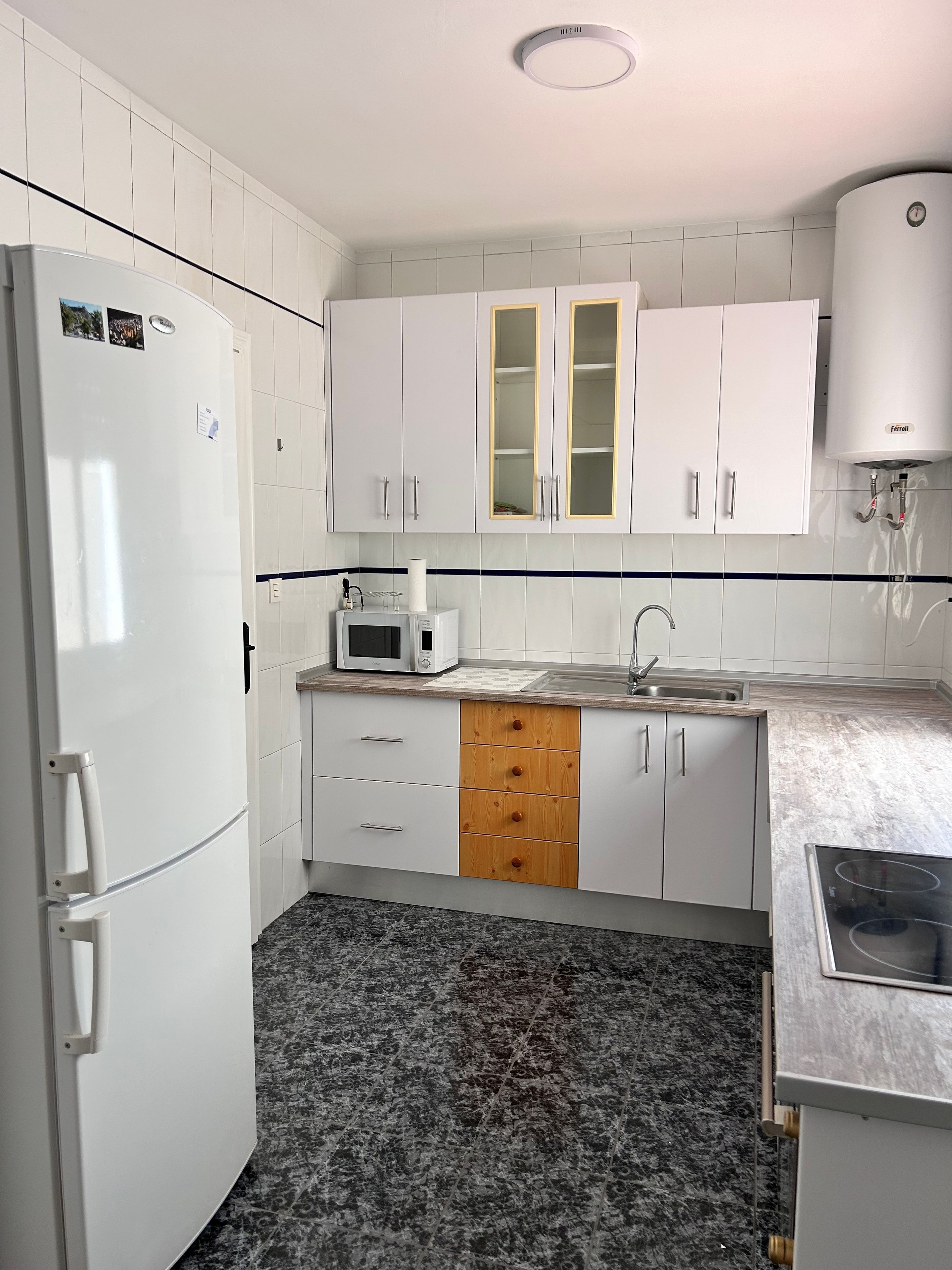 A kitchen with white cabinets, a microwave, a sink, and a stove.