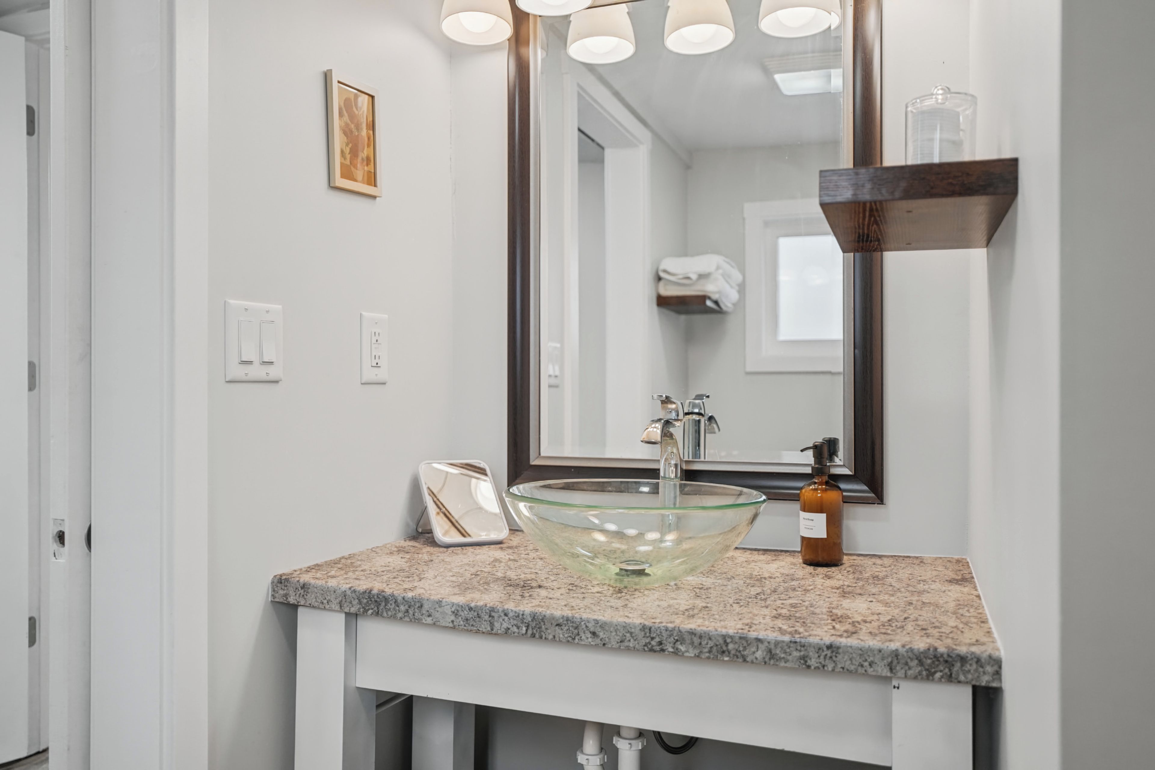 A bathroom with a glass bowl sink, a mirror, and a towel rack.