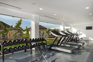 Un gimnasio con cintas de correr, mancuernas y equipamiento de ejercicio.