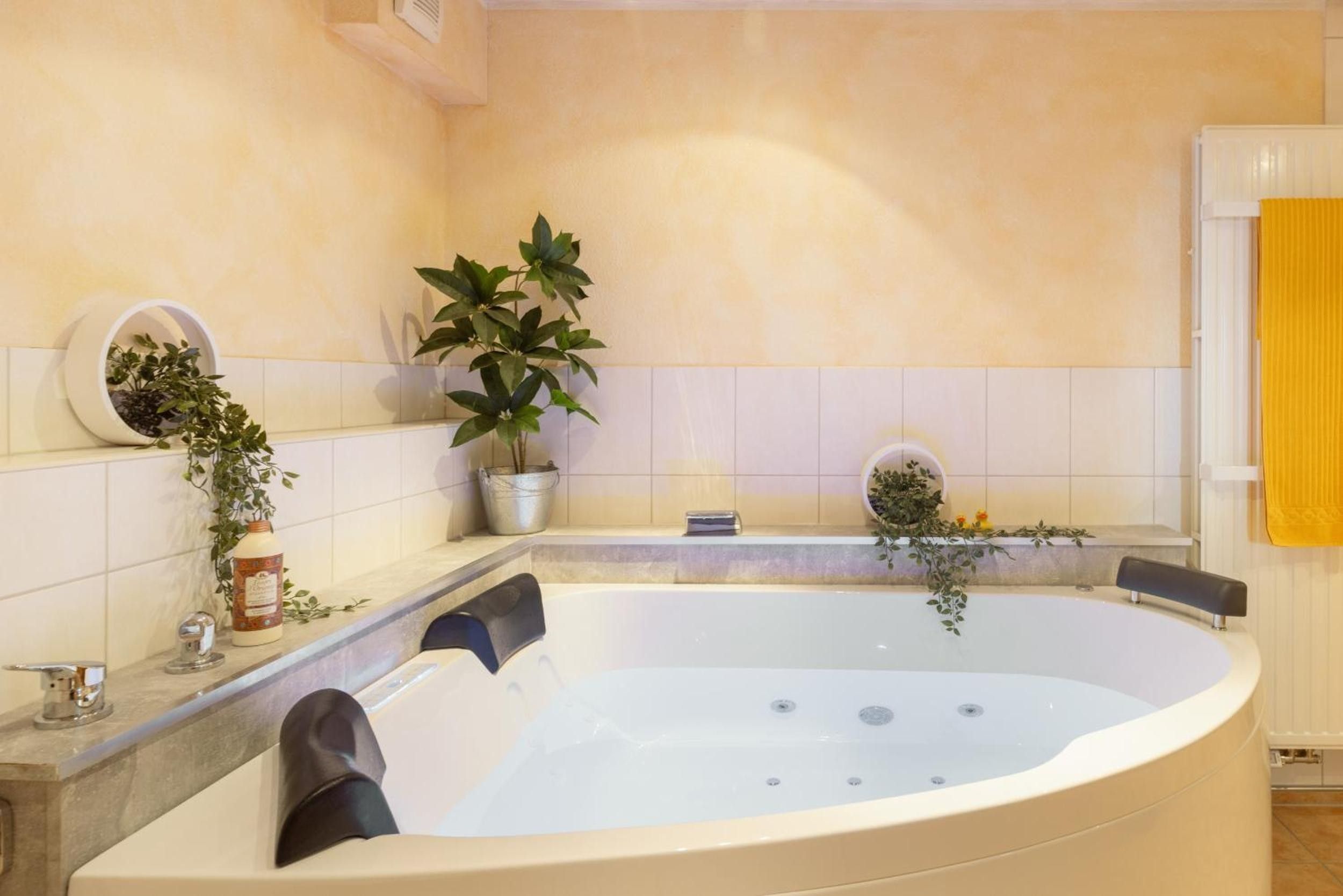 A modern bathroom with a freestanding bathtub, a potted plant, and a yellow towel on the right.