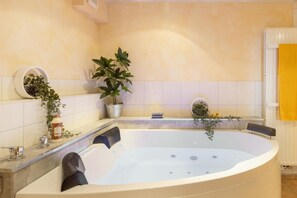 Un baño moderno con una bañera independiente, una planta en maceta y una toalla amarilla a la derecha.