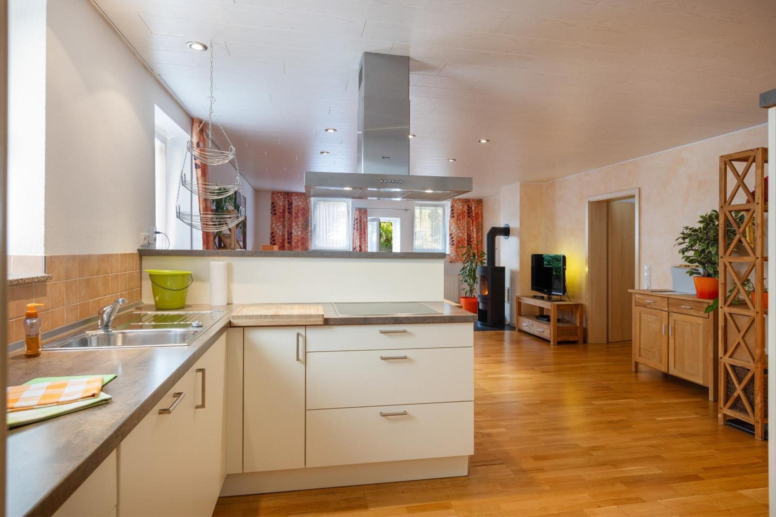 Eine moderne Küche mit einer zentralen Kochinsel, Holzschränken, einem eingebauten Herd und einem Fernseher auf einem Holzboden.