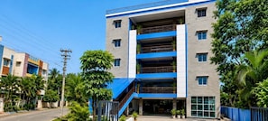 A multi-story building with a blue and white facade, a visible staircase, and surrounding greenery. - Hotel O Atala Main Road (Balianta)