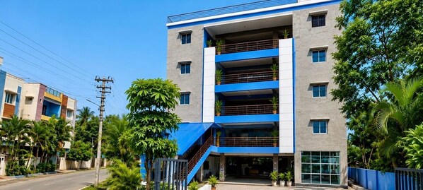 A multi-story building with a blue and white facade, a visible staircase, and surrounding greenery. - Hotel O Atala Main Road (Balianta)