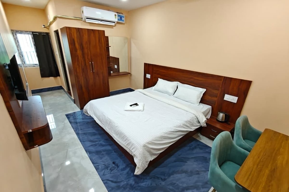 A hotel room with a bed, a desk, a chair, and a wardrobe.