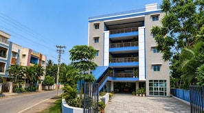A multi-story building with a blue and white facade, a gated entrance, and a paved driveway. - Hotel O Atala Main Road (Balianta)
