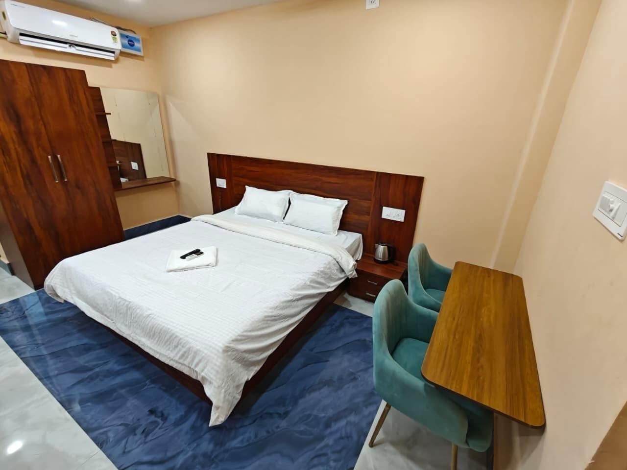 Ein Hotelzimmer mit einem Bett, einem Schreibtisch, einem Stuhl und einer Klimaanlage.