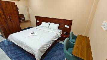 Ein Hotelzimmer mit einem Bett, einem Schreibtisch, einem Stuhl und einer Klimaanlage.