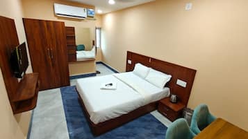 Ein Hotelzimmer mit Bett, Nachttisch, Stuhl, Kleiderschrank und Fernseher.