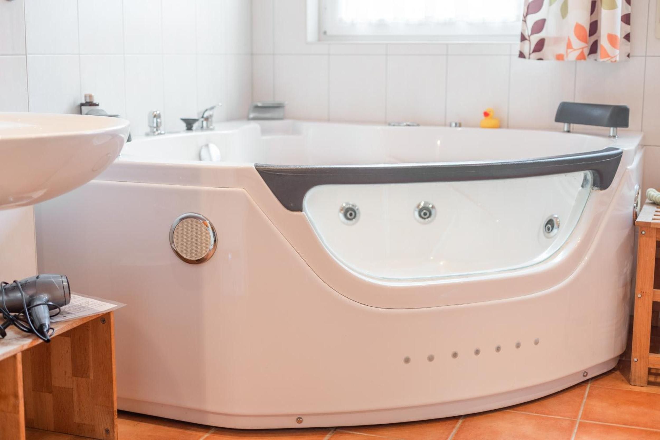 A modern bathroom with a freestanding bathtub, a sink, and a window with a view.