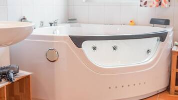 A modern bathroom with a freestanding bathtub, a sink, and a window with a view.