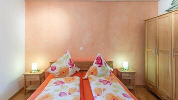 A double bed with floral bedding, two bedside tables with lamps, and a wardrobe.