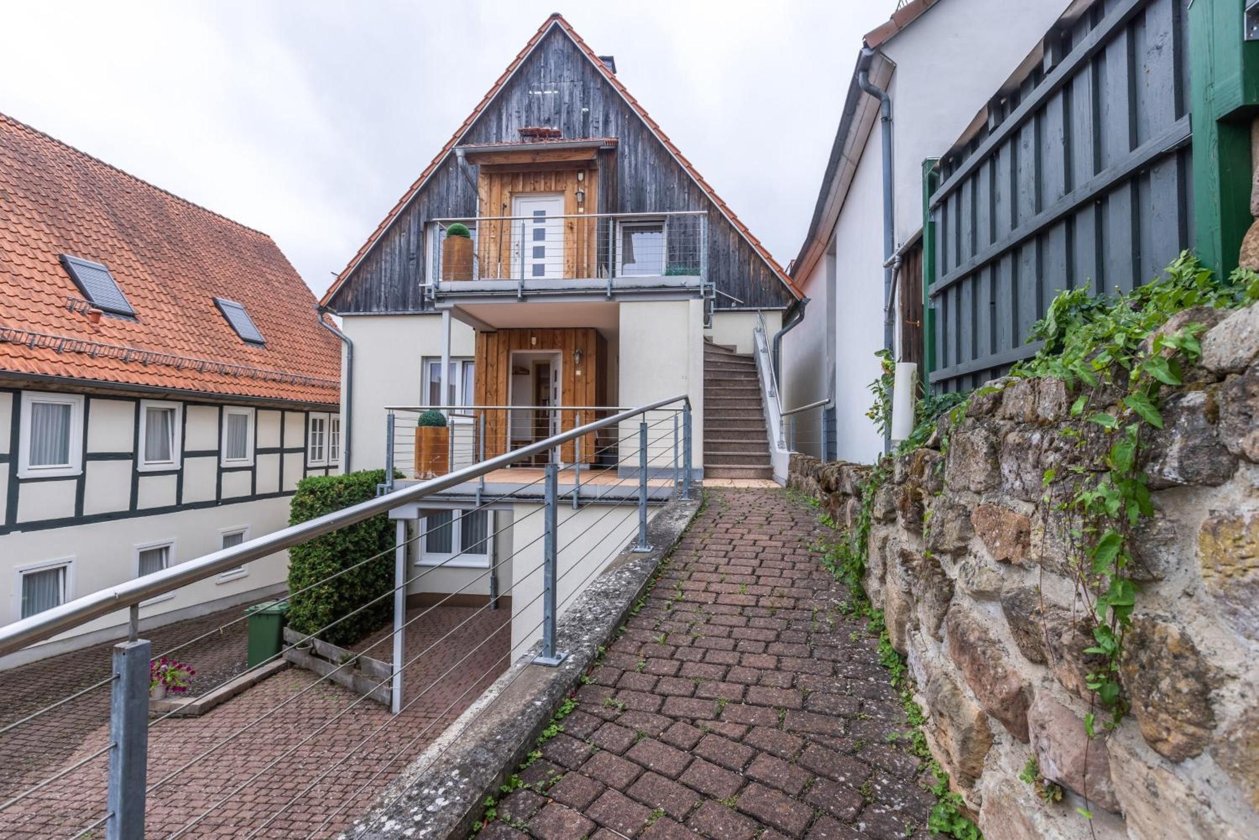 Ein zweistöckiges Gebäude mit Holzfassade, einem Balkon und einer Steinmauer.