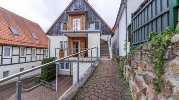 A two-story building with a wooden facade, a balcony, and a stone wall.