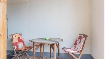 Un pequeño patio con una mesa redonda de madera y dos sillas con tapicería floral.