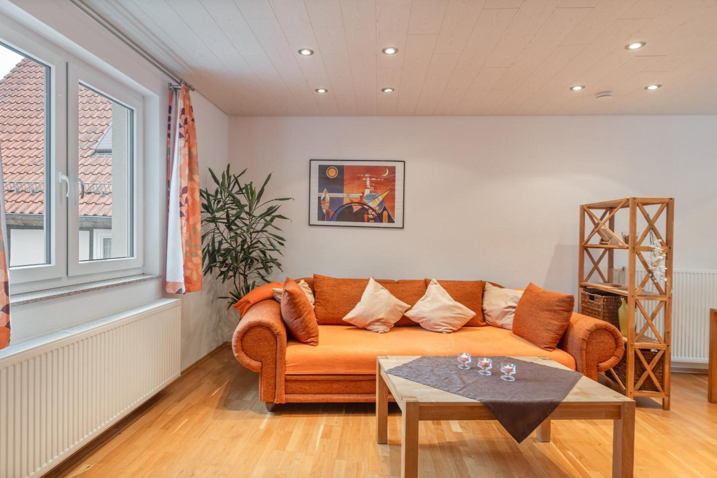 A living room with a sofa, a table, a potted plant, and a painting on the wall.