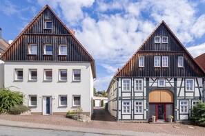 Zwei traditionelle Fachwerkhäuser mit zahlreichen Fenstern und blauem Himmel.