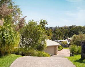 A residential property with a paved driveway leading to a garage, surrounded by lush greenery and trees. - Binnea Beach House & 1 Bedroom Garden Suite (Sunshine Coast)