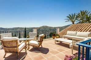 A terrace with wicker furniture, a white sofa, and a view of the hills. - Villa 'Casa Bergerac' with Sea View, Wi-Fi and Air Conditioning (Cómpeta)