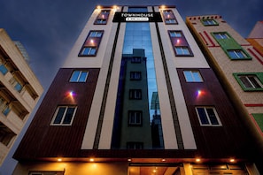 Un edificio de varios pisos con fachada central de vidrio y numerosas ventanas.