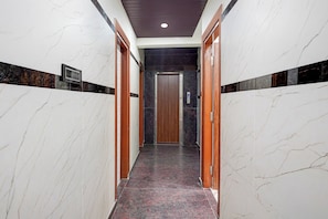 Un pasillo con paredes de mármol y una puerta de madera al final.