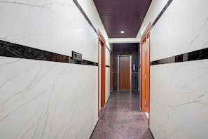Un pasillo con paredes de mármol y una alfombra roja que conduce a un ascensor.