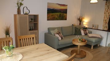 A cozy living room with a sofa, a dining table, and a bookshelf.