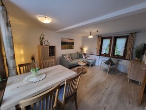 A cozy living room with a dining table, sofa, and a window with curtains.
