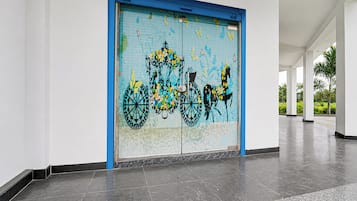 A building entrance with a large blue-framed door featuring a colorful mural of a bicycle and horse.