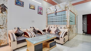 Una sala moderna con un conjunto de sofás, una mesa de centro de cristal y decoración en la pared.