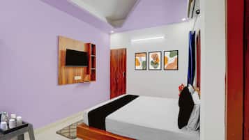 A bedroom with a bed, a TV mounted on the wall, and artwork on the wall.