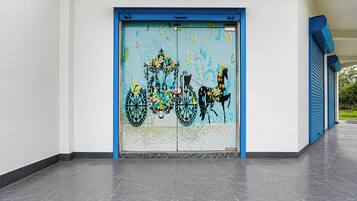 Ein Gebäudeeingang mit einer blauen Tür, verziert mit einem farbenfrohen Wandbild von Fahrrädern und Blumen.