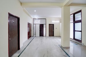 A hallway with doors numbered 101 and 103, a marble floor, and a ceiling with recessed lighting. - Super Hotel O Patel Nagar Patna (Patna)