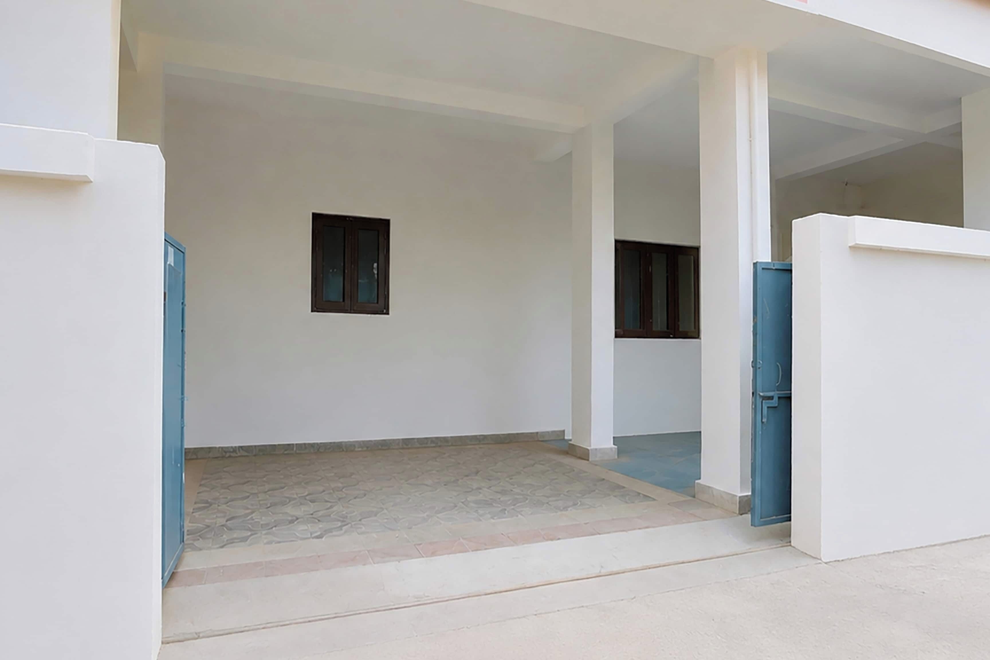 An empty room with a tiled floor, two windows, and a blue door.